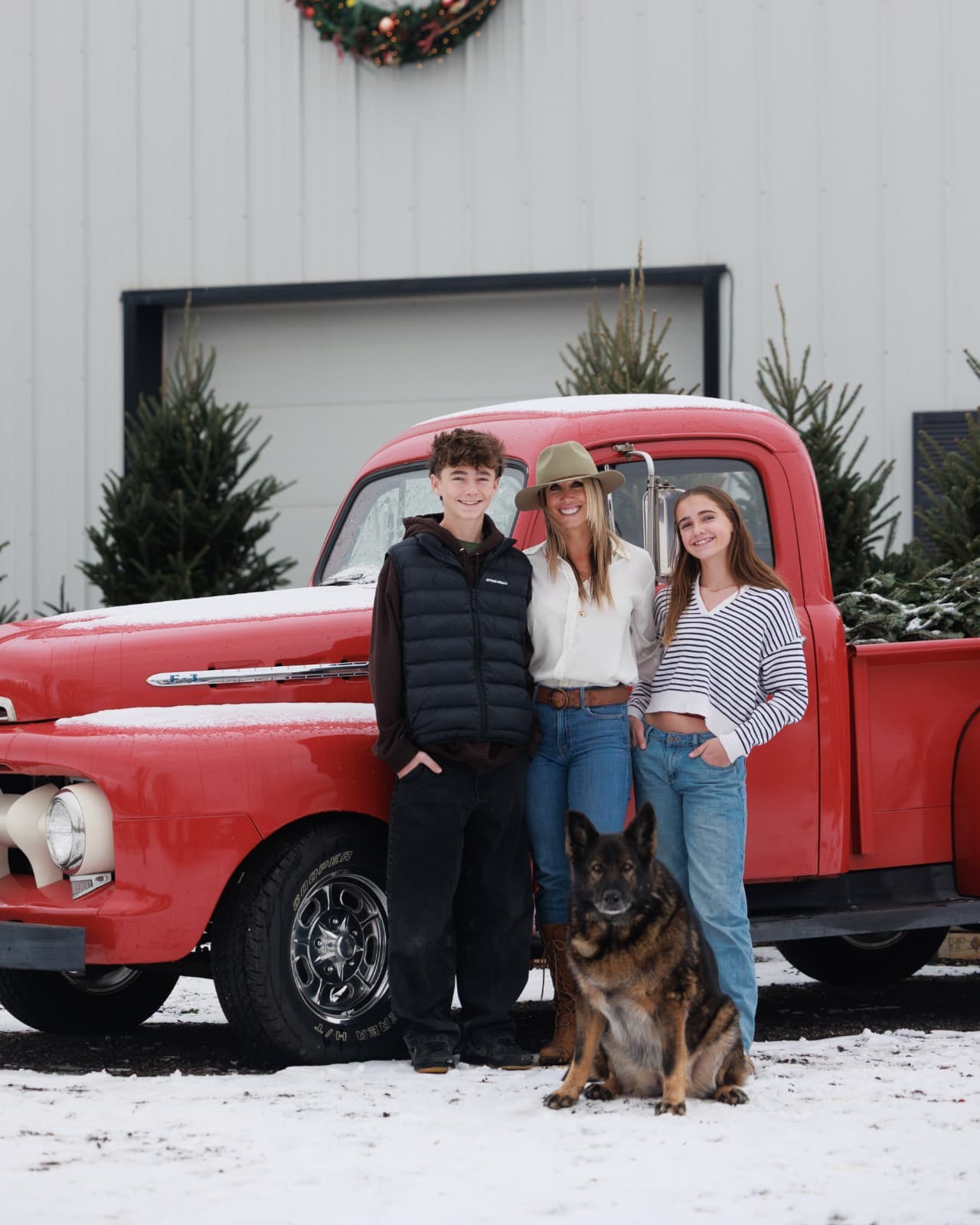 April Ramker with her kids and their dog by a red truck in the snow